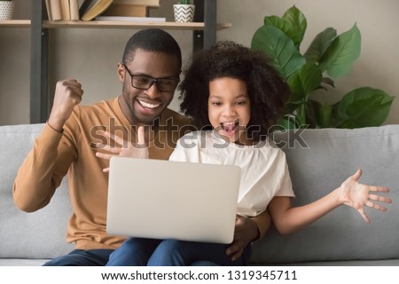 Excited african father and kid girl feel winners looking at computer screen, happy black dad with child daughter using laptop rejoice online game win, great internet news, celebrate victory together