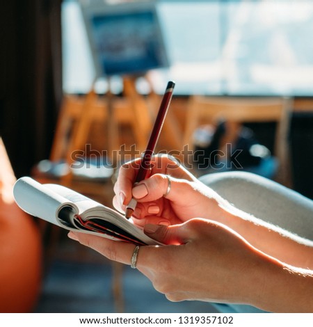 Fine artist sketching. Studio workspace. Female painter doing pencil sketch in pad.