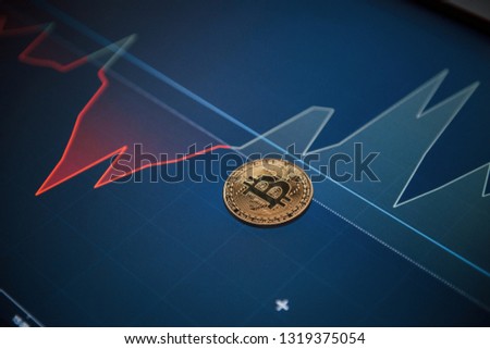 Modern digital currency. Picture of golden bitcoin lying on the display with graphs in office.