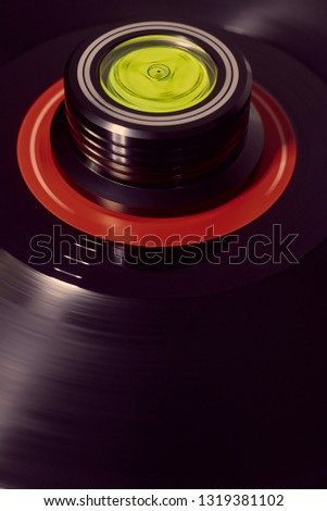 Vertical background of a rotating record and weight with a flare to the left.