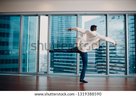 Jumping young man on the background of a skyscraper indoors.