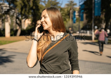 Beautiful and cheerful young woman talking on a phone in city. Lifestyle portrait. 
