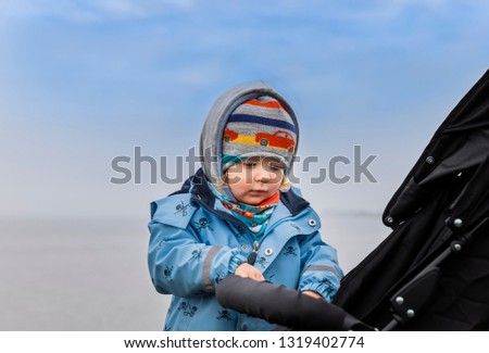 Toddler girl examining safety belt and buckle of buggy – Hindeloopen, Friesland, Netherlands