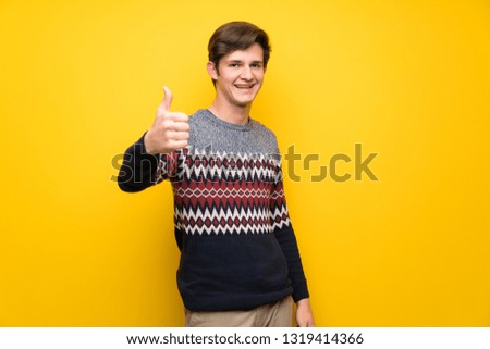 Teenager man over yellow wall with thumbs up because something good has happened