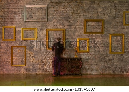 Empty picture frames on the brick wall and forged, chest with candlesticks, motion man.