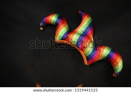 carnival jester hat on black background. Rainbow coloured hat. At a pride parade