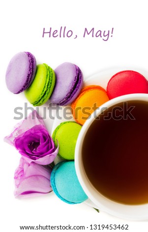 Cake macaron or macaroon on white plate with cup of coffee isolated on white, colorful almond cookies, pastel colors, violet spring flower. Top view with text hello May.