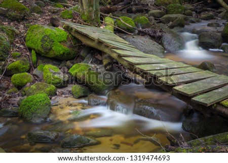 Small wooden bridge over a fast stream deep in the forest.