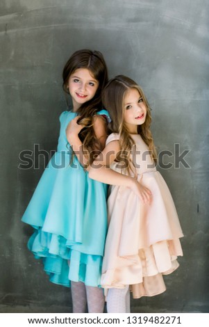 Two Caucasian sisters posing for picture during family photo shooting, the girls turned their backs to each other