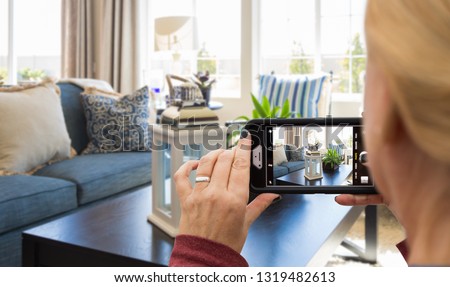 Woman Taking Pictures of A Living Room in Model Home with Her Smart Phone.