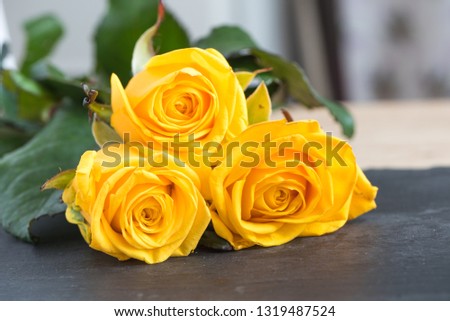 Five large buds of yellow roses. Bouquet of flowers. Sunny yellow garden roses on a black plate. Love theme. Celebration. Postcard