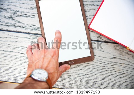 A modern digital tablet with a bright with a white screen lying on an old vintage wooden desk with pen
