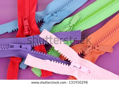 Multicolored zippers on purple background