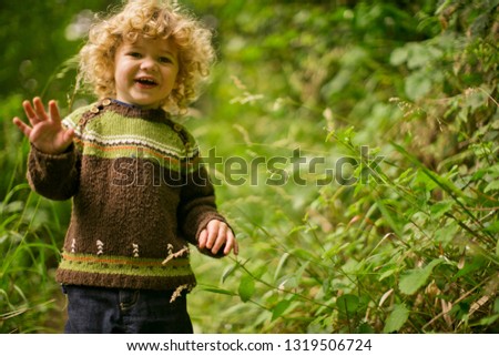 Portrait of a smiling young boy exploring among lush plants.