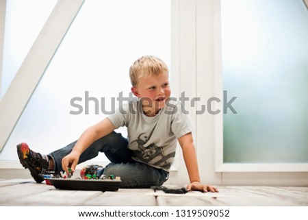 Boy playing with his toys on the floor.