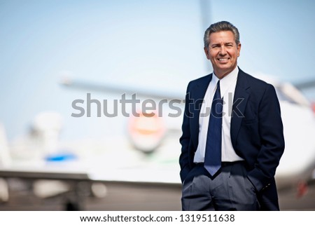 Businessman standing in front of a private jet and smiling
