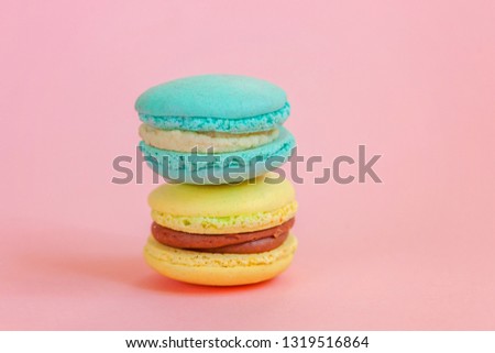 Sweet almond colorful unicorn blue yellow macaron or macaroon dessert cake isolated on trendy pink pastel background. French sweet cookie. Minimal food bakery concept. Copy space