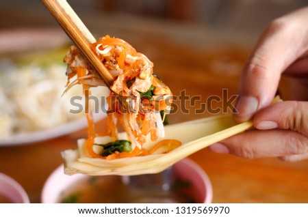 a picture show using chopstick with fried nooddle that called Pad Thai or Thai fried nooddle with eggs and lotus petal