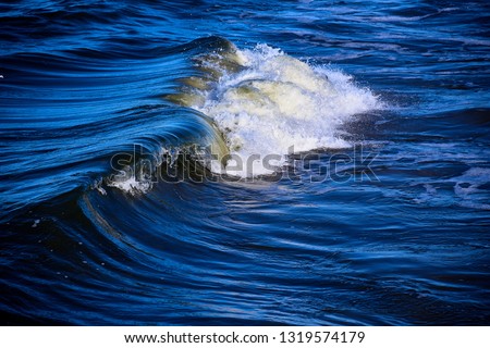 breaking wave in stormy blue green sea