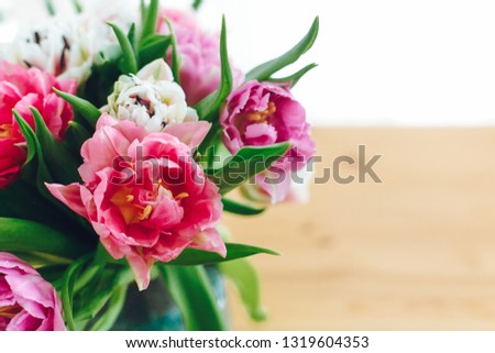 Beautiful double peony tulips in light. Colorful pink and purple tulips bouquet in vase on table with copy space. Happy mothers day. International women's day. Hello Spring. Greeting card
