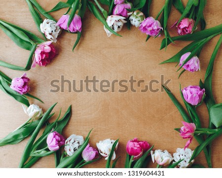 Beautiful double peony tulips frame flat lay on wooden table, space for text. Colorful pink and purple tulips. Happy mother's day. International women's day. Hello Spring. Floral Greeting card