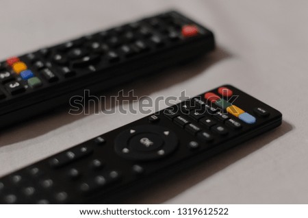 Two black TV remote controllers isolated on the grey background. Watching a movie concept.