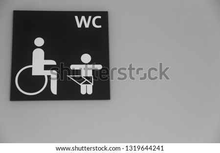 Toilet sign at bathroom facility for wheelchairs and babies. Concept of extra room in toilets for handicapped or disabled people and changing diapers station for babies nappies. WC plaques at airports