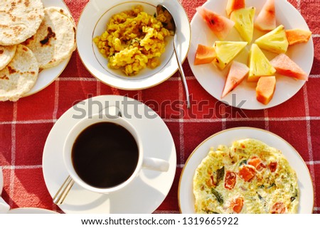 Top view breakfast set traditional  Srilanka style have blak coffee, rotti, dahl, omelette, sliced tropical fruit on red pattern white square line, crop picture, South Asian food concept 