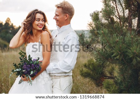 Beautiful bride in a white dress. Couple in a summer field. Woman with a bouquet of flowers