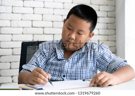 child boy doing homework writing and reading drawing at home
