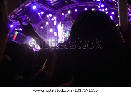 Silhouettes of crowd at concert, People with hands up.