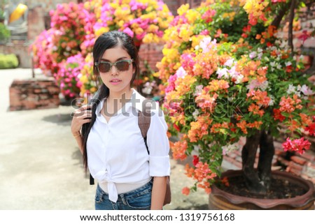 portrait of beautiful woman with sum glasses having a happy time and enjoying among flowers in temple