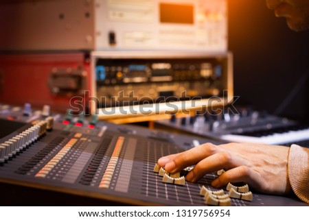 male sound engineer, dj hand working on audio mixing console in recording, editing, broadcasting studio