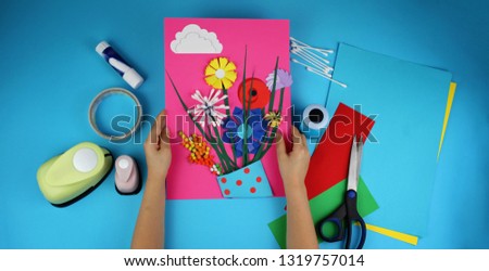 Cute 5-6 years old girl making spring DIY flowers with colored paper for her mom in Mothers Day, decorative punchers to create fun and easy, concept for kindergarten, top view image, banner format
