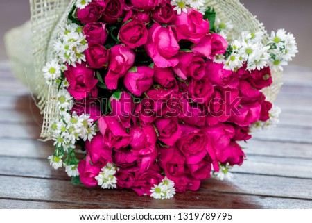 The background of a bouquet of flowers (red rose, pink) that is placed on a wooden table or decorated in a garden, coffee shop, dessert For the beauty of the witness