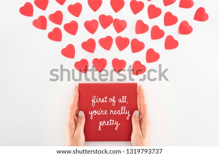 cropped shot of woman holding envelope with "first of all, you are really pretty" lettering under dozen red heart symbols isolated on white, st valentine day concept