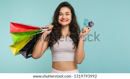 Happy woman with multicolored packages and credit card on a yellow background, shopping - Image