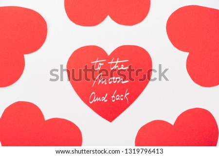 background with heart shaped paper cards isolated on white, st valentines day concept with "to the moon and back" lettering