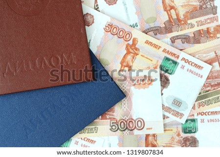 Two Russian education documents with money in them as a symbol of expensive educational system