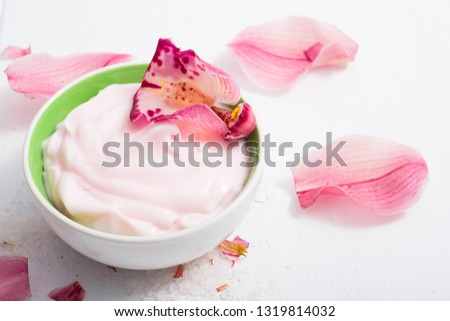 cosmetic cream with pink flower petals, white wood table