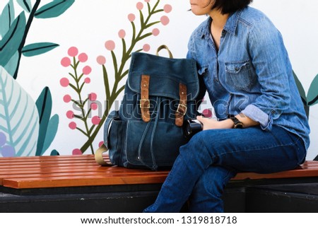 Beautiful woman wearing jean with dark blue backpack waiting for traveling companions, Travel concept