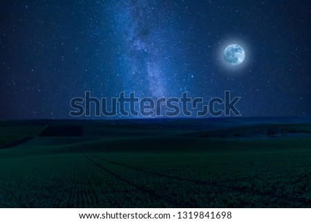 Nidht landscape with green fields on hills and moon, stars in sky over farmland