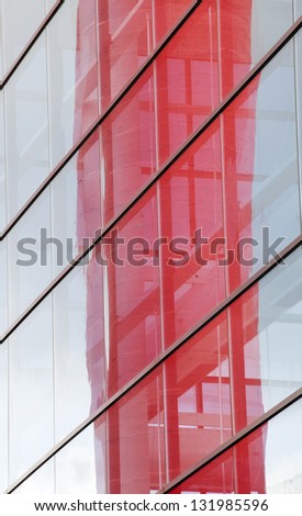 Abstract photo of a contemporary building with blue windows and red reflection.