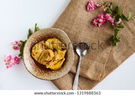 Cheese Wonton in shabu soup with burlap texture and Mexican creeper flower on white background.