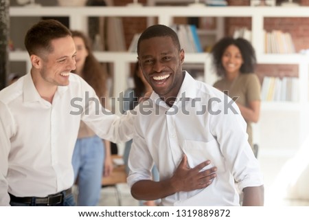 Successful proud black businessman looking at camera celebrating victory got promotion or reward, happy african employee taking congratulations from colleague on professional achievement in office Royalty-Free Stock Photo #1319889872