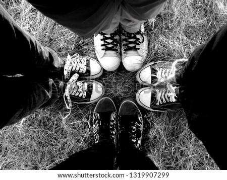 Four pairs of legs wearing sneakers. Black and white photo of friends with sports shoes
