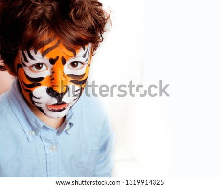 little cute boy with faceart on birthday party close up, orange adorable tiger facepaint