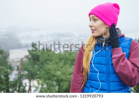 Outdoor sport exercises, sporty outfit ideas. Woman wearing warm sportswear training exercising and listening to music outside during autumn.