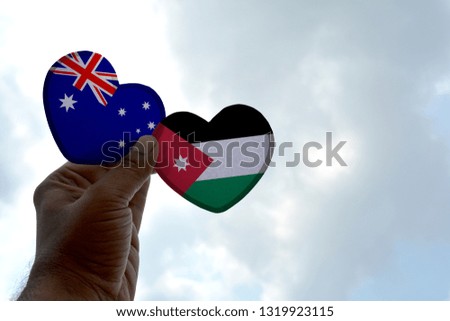 Hand holds a heart Shape Australia and Jordan flag, love between two countries