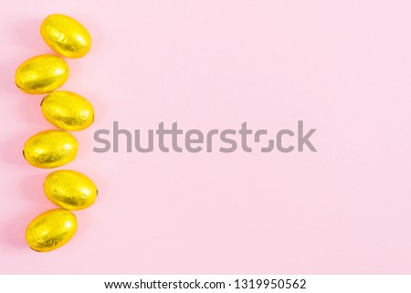 Golden easter eggs over pink background with copy space, flat lay style